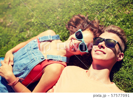 happy teenage couple lying on grass at summer 57577091