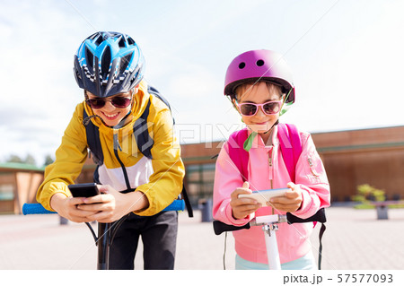 school children with smartphones and scooters 57577093