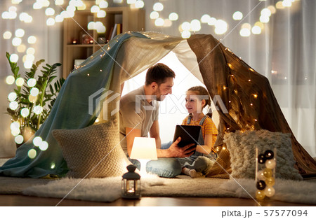 family with tablet pc in kids tent at home 57577094