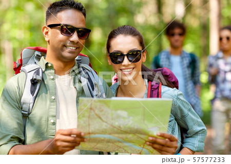 friends with map and backpacks hiking in forest 57577233