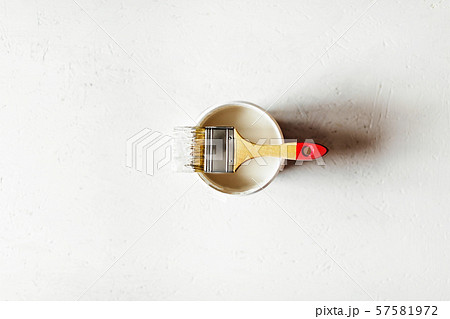 Construction brush with red handle on paint jar on painted plywood. 57581972