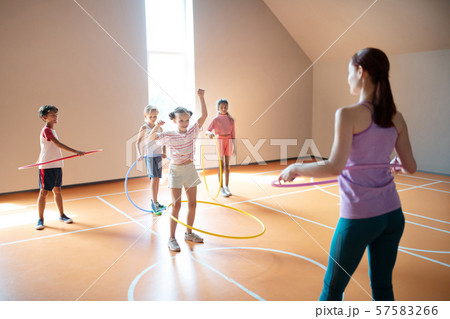 Children trying to roll hula-hoop at the PE lesson 57583266