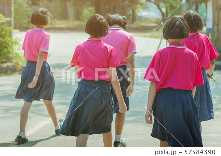 Back view of happiness primary girl students in pink shirt and blue skirt walk to classrooms with their friends. Back view of happiness primary girl students in pink shirt and blue skirt walk to classrooms with their friends. 57584390