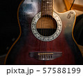 Acoustic guitar resting against a wooden background  57588199
