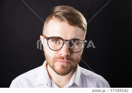 Portrait of young serious bearded man and in glasses over the black background 57589582