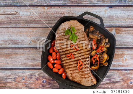 Beef steak lies on a black grill pan. 57591356