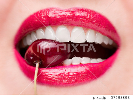 The girl bites a ripe cherry. Cherry in mouth 57598398