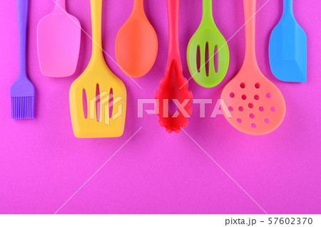 bright multi colored kitchen utensils on purple background with copy space 57602370