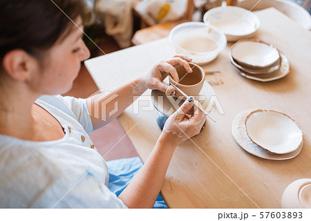 Female potter skins pot with a spatula, pottery Female potter skins pot with a spatula, pottery 57603893