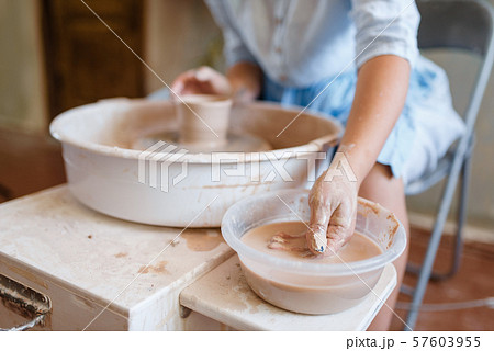 Female master making a pot on pottery wheel 57603955