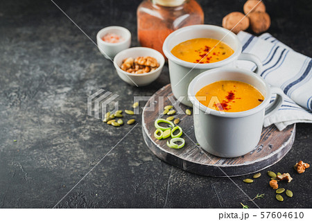 Pumpkin soup in a metal mugs on wooden board Pumpkin soup in a metal mugs on wooden board 57604610