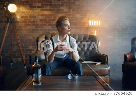 Woman in shirt and trousers with whiskey and cigar Woman in shirt and trousers with whiskey and cigar 57604920