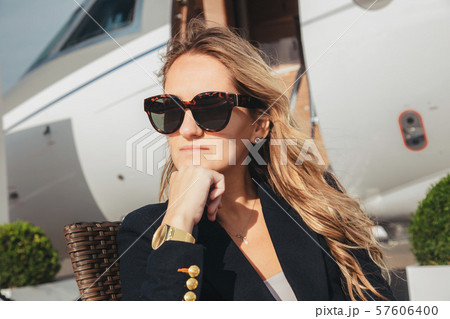 beautiful businesswoman is seating near the business jet airplane at a sunny day beautiful businesswoman is seating near the business jet airplane at a sunny day 57606400
