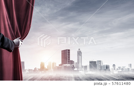 Business city behind red curtain and hand holding it 57611480