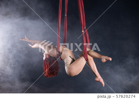 Female athletic, sexy and flexible aerial circus artist with redhead dancing in the air on the silk Female athletic, sexy and flexible aerial circus artist with redhead dancing in the air on the silk 57620274
