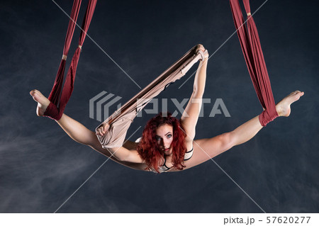Female athletic, sexy and flexible aerial circus artist with redhead dancing in the air on the silk 57620277