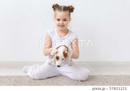 Dogs, pets and animal concept - Little child girl sitting with puppy Jack Russell Terrier 57621221