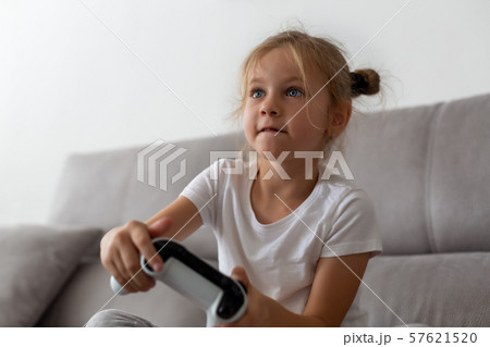 Competitive girl playing with gamepad on couch Competitive girl playing with gamepad on couch 57621520