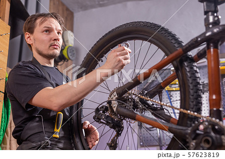 Service, repair, bike and people concept - Mechanic repairing a mountain bike in a workshop Service, repair, bike and people concept - Mechanic repairing a mountain bike in a workshop 57623819