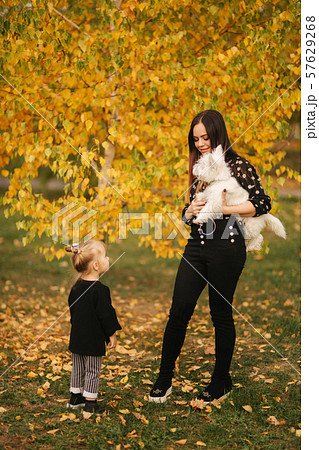 Mother and little daughter walking with her dog in autumn weather. Stylish little daughter and her Mother and little daughter walking with her dog in autumn weather. Stylish little daughter and her 57629268