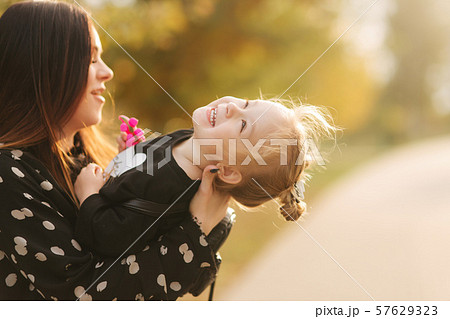 Mother and little daughter walking in autumn weather. Stylish little daughter and her beautiful 57629323