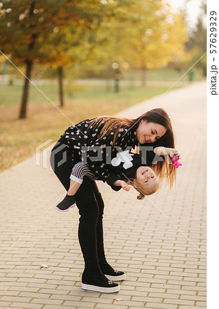 Mother and little daughter walking in autumn weather. Stylish little daughter and her beautiful 57629329