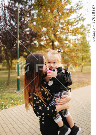 Mother and little daughter walking in autumn weather. Stylish little daughter and her beautiful 57629337