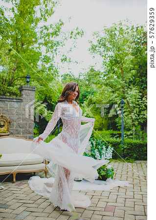 Seductive young bride in white negligee posing with big piece of white fabric Seductive young bride in white negligee posing with big piece of white fabric 57629359