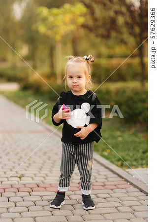 Happy little girl walking in the park in autumn. Beautiful female kid on yellow background Happy little girl walking in the park in autumn. Beautiful female kid on yellow background 57629366