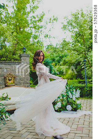 Seductive young bride in white negligee posing with big piece of white fabric Seductive young bride in white negligee posing with big piece of white fabric 57629368