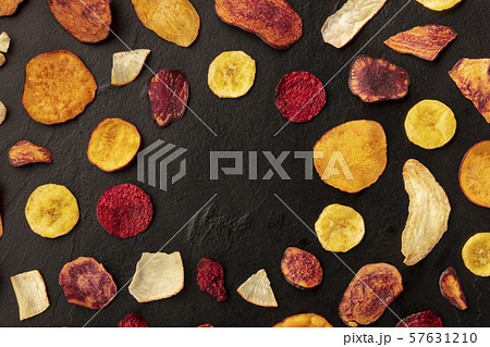 Dry fruit and vegetable chips, healthy vegan snack, an organic food flat lay pattern on a black Dry fruit and vegetable chips, healthy vegan snack, an organic food flat lay pattern on a black 57631210