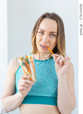 Diet concept - Healthy lifestyle woman eating vegetables smiling happy indoors. Young female eating Diet concept - Healthy lifestyle woman eating vegetables smiling happy indoors. Young female eating 57634498