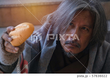 Homeless man is sitting down on staircase in town.He is Show bread.He is very unhappy.focus is bread .poverty,despair, Photo Sympathetic and hope concept. 57636022