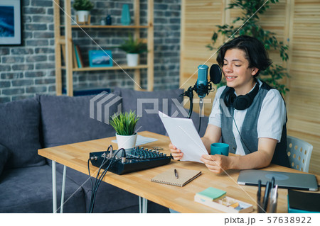 Smiling boy reading aloud in microphone recording podcast in modern studio 57638922
