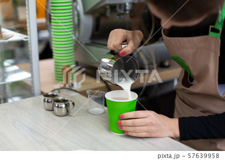 Barista in an apron pours milk into a green Barista in an apron pours milk into a green 57639958
