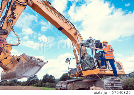 Construction worker on excavator planning the work to be done Construction worker on excavator planning the work to be done 57640326