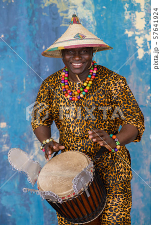 Handsome african drummer weared in traditional costume playing on djembe drum Handsome african drummer weared in traditional costume playing on djembe drum 57641924