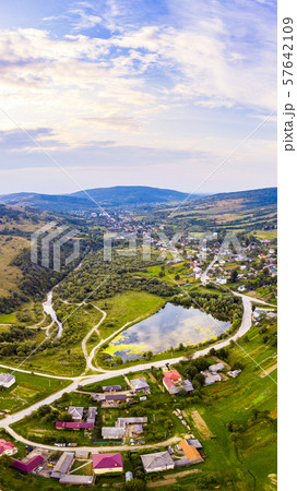 Vertical landscape of settlement in valley between mountains. Sunset time, end of summer. Aerial 57642109