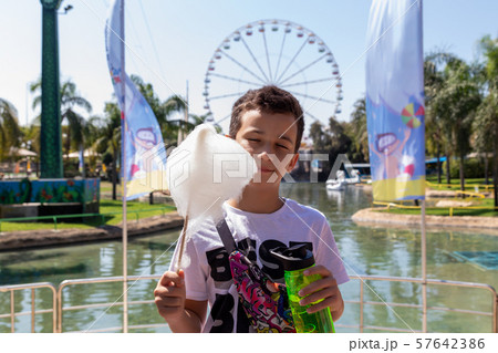 Cute boy eats cotton candy outdoors. Happy childhood. Funny kid in a park 57642386