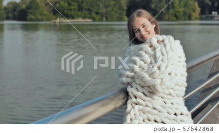 The girl is walking around the city lake, wrapped in a white plaid of merino wool in the early The girl is walking around the city lake, wrapped in a white plaid of merino wool in the early 57642868