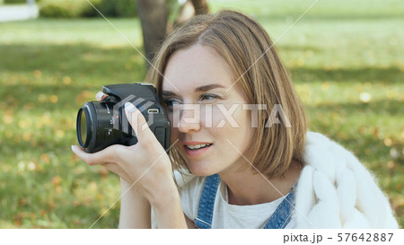 The girl takes pictures of nature in the park in the summer. The girl takes pictures of nature in the park in the summer. 57642887