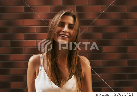 Cheerful beauty. Beautiful girl posing over brick background 57651411