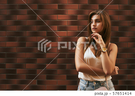 Looking at you. Beautiful stylishly dressed girl posing over brick background Looking at you. Beautiful stylishly dressed girl posing over brick background 57651414
