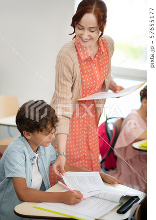 Red-haired teacher smiling while handing in tests to schoolboy Red-haired teacher smiling while handing in tests to schoolboy 57655177
