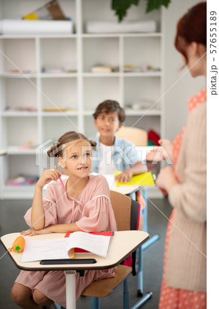 Attentive schoolgirl wearing pink dress listening to teacher Attentive schoolgirl wearing pink dress listening to teacher 57655189