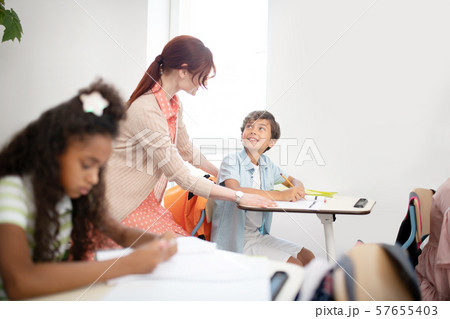 Dark-haired boy looking at teacher explaining him material 57655403
