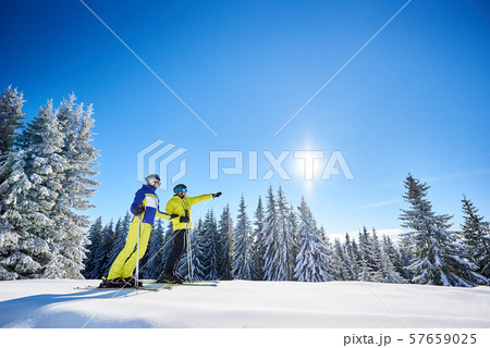 Couple of skiers on skis on hill at ski resort. Recreational activities in mountains concept. Low 57659025
