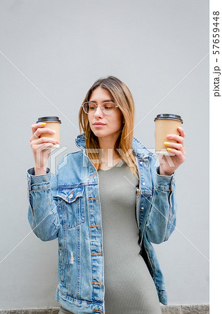 Blonde girl with paper cups of coffee on grey Blonde girl with paper cups of coffee on grey 57659448