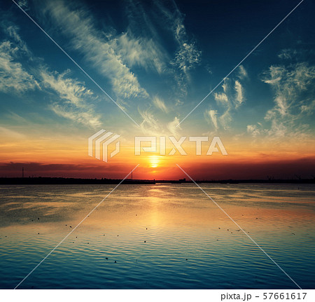 low orange sunset in dramatic clouds over river low orange sunset in dramatic clouds over river 57661617
