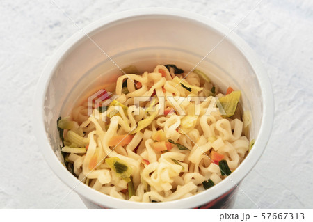 A close-up of a plastic cup of instant ramen noodles with carrot and chives 57667313